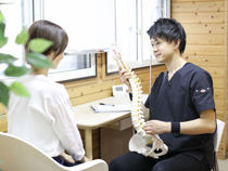 脊椎の模型を使い説明するようす